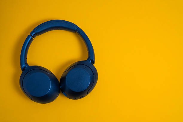 Blue wireless headphones on a yellow background, representing music, technology, and audio listening