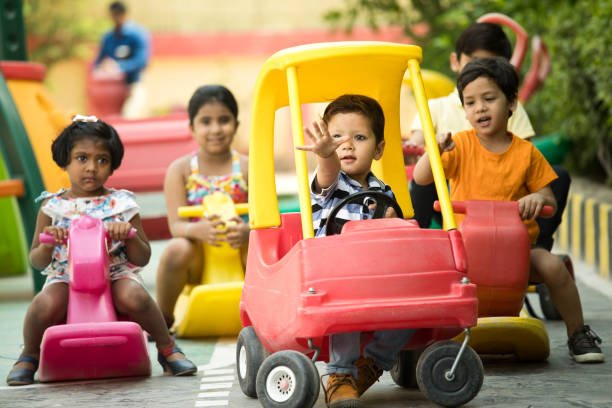 Preschool boys and girls having fun playing on toy car and rocking horse