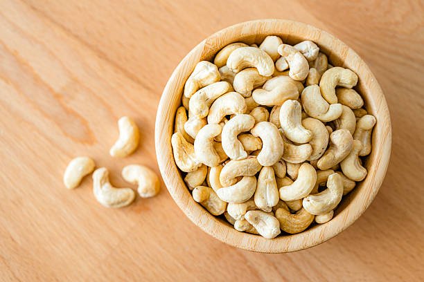 Bowl filled with organic cashews shot from above on wood table